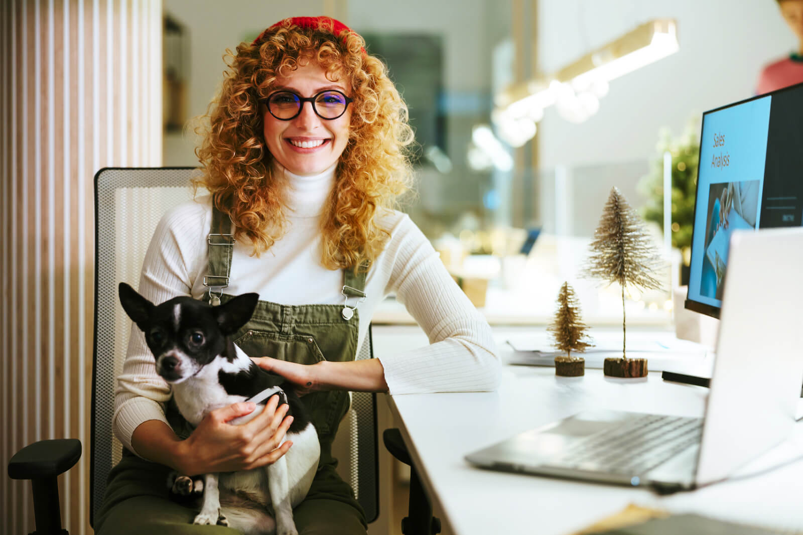 A header image for Slido's blog post about Christmas quiz ideas depicting a young pretty woman sitting in her office in front of a computer during Christmas period